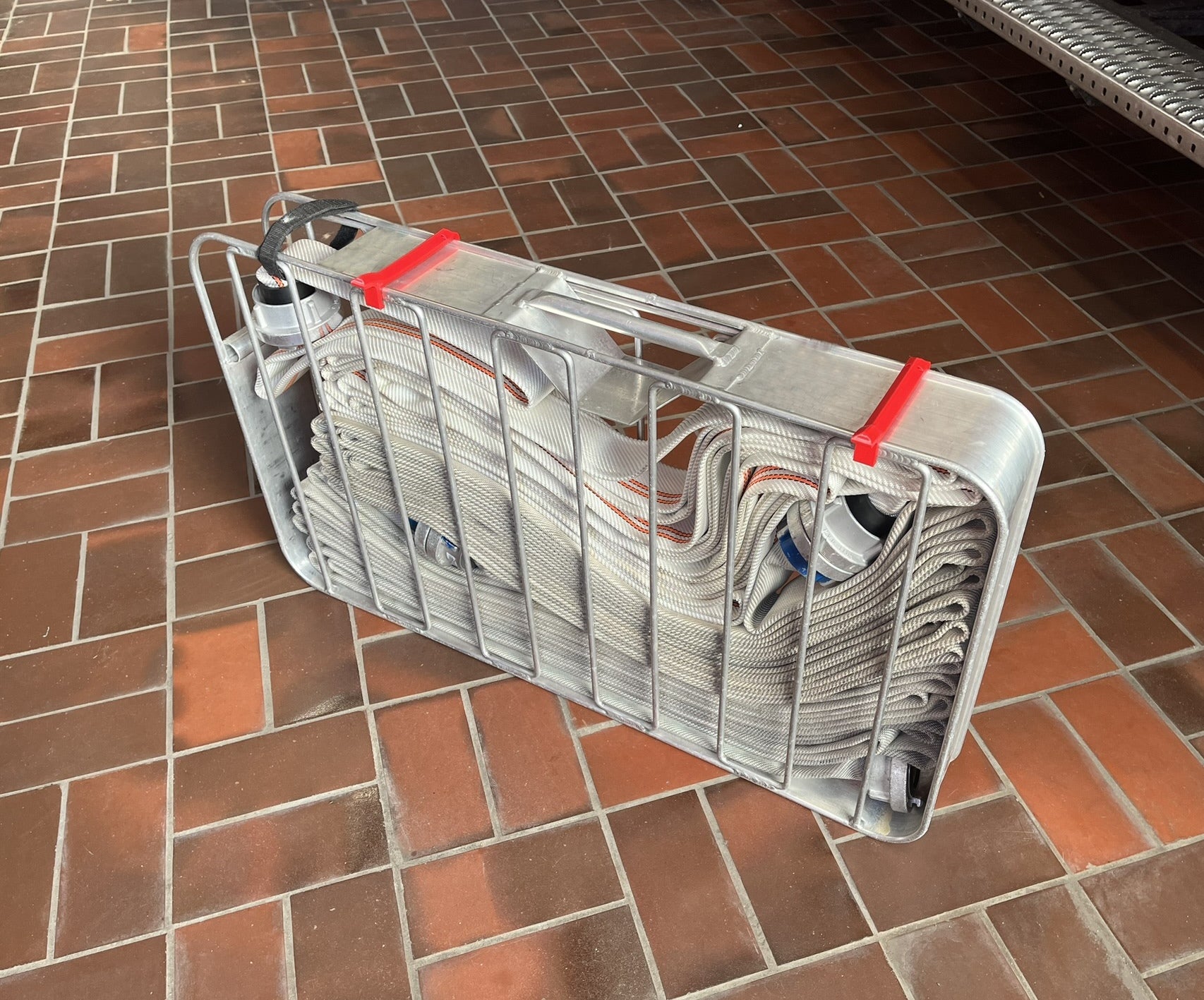 flache Variante Clip / Schnellverschluss für Schlauchtragekorb nach DIN 14827 im eingebauten Zustand. Der Clip ermöglicht ein leichtes öffnen und verschließen der Schlauchtragekörbe, auch mit Handschuhen und unter Stress